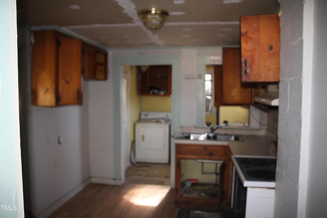 kitchen with washer / dryer, light wood-type flooring, sink, and range hood