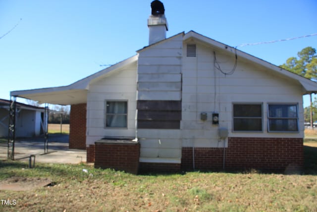 back of property with a carport and a lawn