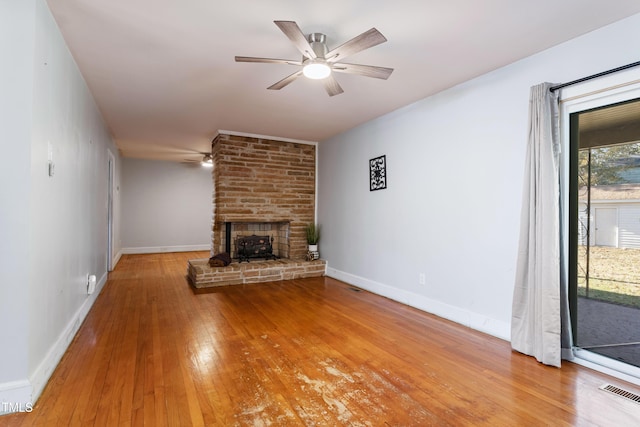 unfurnished living room featuring light wood-type flooring, a large fireplace, and ceiling fan