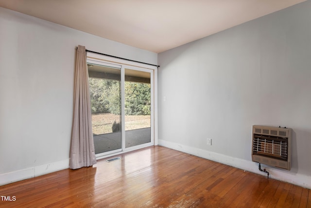 unfurnished room featuring wood-type flooring and heating unit