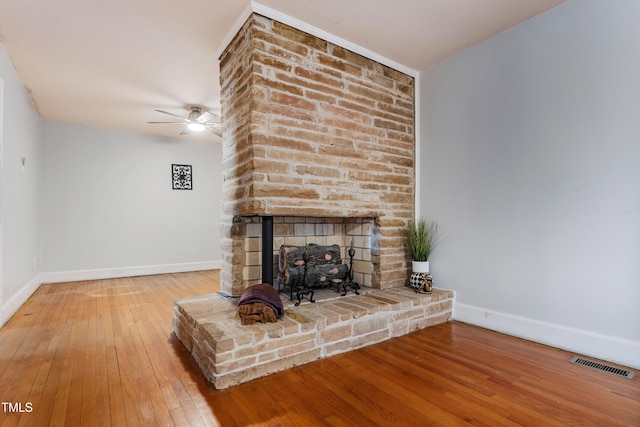 unfurnished living room featuring a large fireplace, ceiling fan, and hardwood / wood-style floors