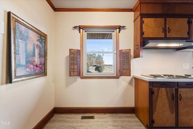 kitchen with light hardwood / wood-style floors, stainless steel gas stovetop, and crown molding