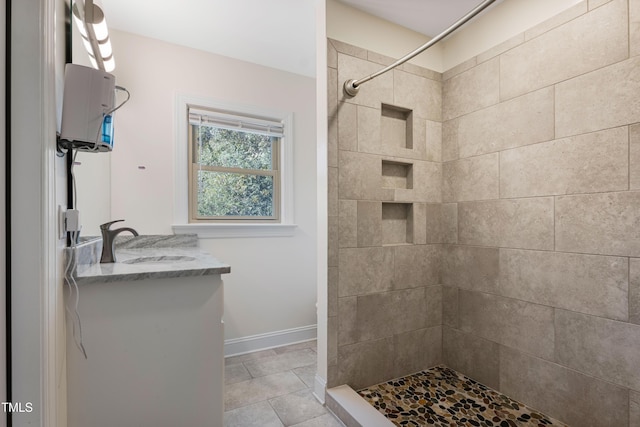 bathroom featuring tiled shower, vanity, and tile patterned flooring