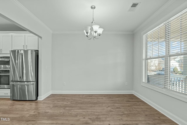 unfurnished dining area with an inviting chandelier, ornamental molding, and light wood-type flooring