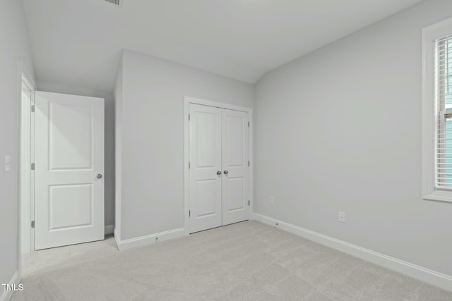 unfurnished bedroom featuring light carpet, a closet, and multiple windows