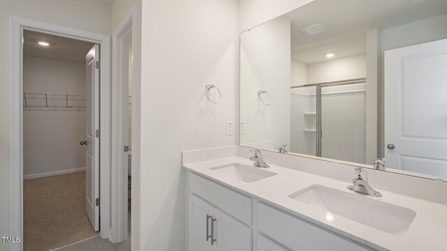 273 Hanging Elm Ln, Fuquay Varina, NC 27526 - bathroom with double vanity, a walk in closet, and an enclosed shower