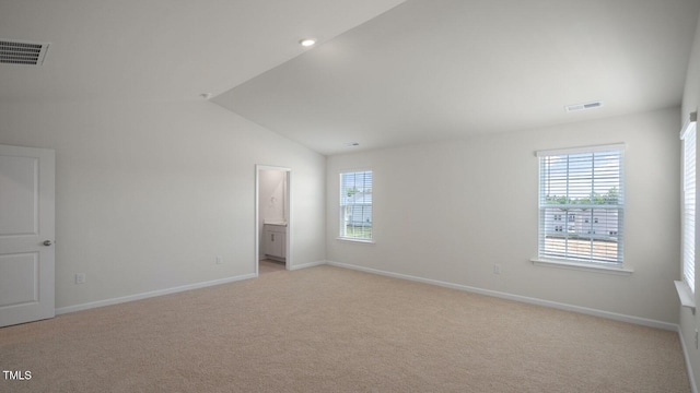 carpeted spare room with plenty of natural light and vaulted ceiling