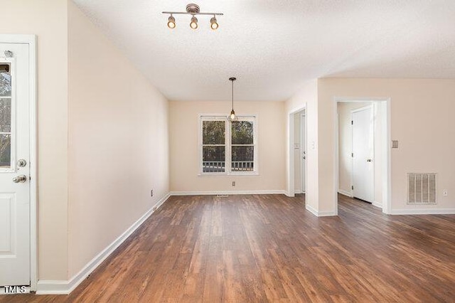 unfurnished dining area featuring a textured ceiling and dark wood-type flooring