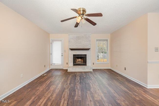 unfurnished living room featuring a textured ceiling, dark hardwood / wood-style flooring, a brick fireplace, and ceiling fan