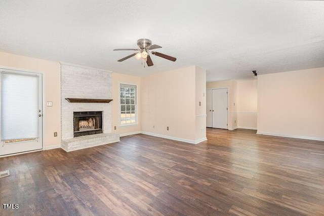 unfurnished living room with a fireplace, ceiling fan, dark hardwood / wood-style flooring, and a textured ceiling