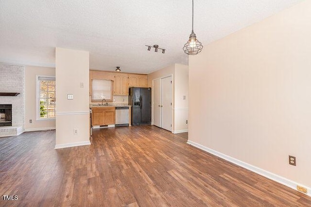 kitchen featuring dishwasher, hanging light fixtures, black fridge, dark hardwood / wood-style flooring, and a textured ceiling