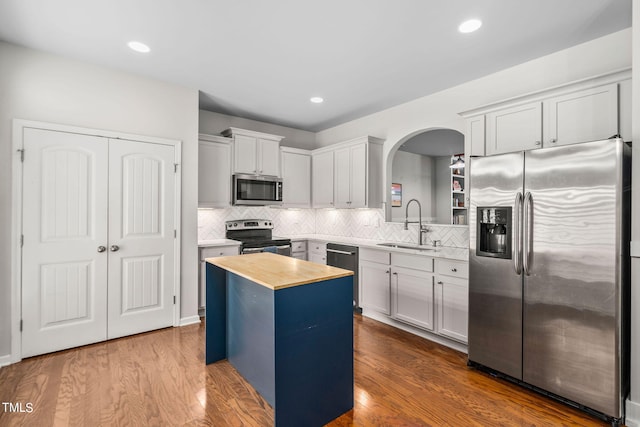 kitchen with sink, stainless steel appliances, wood counters, backsplash, and a kitchen island