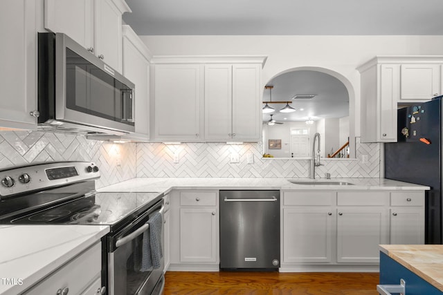 kitchen featuring wooden counters, white cabinets, sink, ceiling fan, and stainless steel appliances