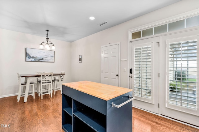 kitchen with blue cabinetry, pendant lighting, butcher block counters, and wood-type flooring