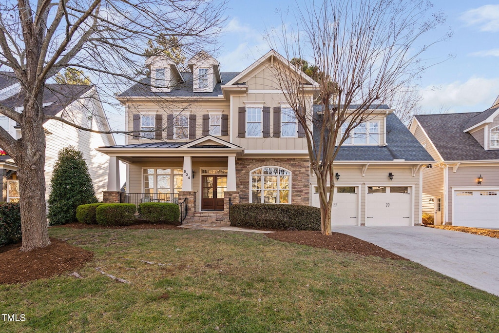 view of front of home with covered porch, a garage, and a front lawn