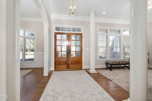 entrance foyer with dark wood-type flooring, an inviting chandelier, french doors, ornamental molding, and decorative columns