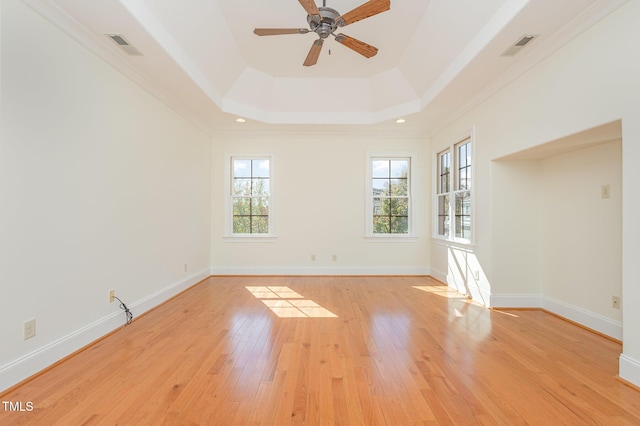 unfurnished room featuring light wood-type flooring, a raised ceiling, ceiling fan, and crown molding