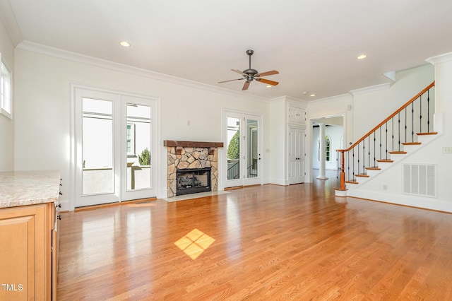 unfurnished living room featuring ceiling fan, a fireplace, light wood-type flooring, and ornamental molding