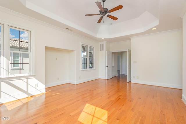 spare room featuring a raised ceiling, light hardwood / wood-style flooring, and ornamental molding