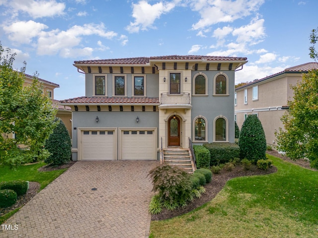 mediterranean / spanish house featuring a balcony, a garage, and a front lawn