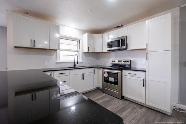 kitchen featuring white cabinets, wood-type flooring, sink, and appliances with stainless steel finishes