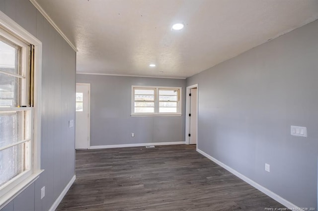 empty room with dark hardwood / wood-style flooring and ornamental molding