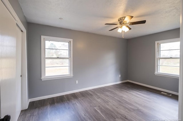 unfurnished room with a textured ceiling, plenty of natural light, and dark hardwood / wood-style floors