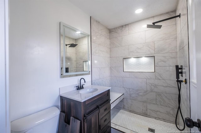 bathroom with tile patterned flooring, vanity, toilet, and tiled shower