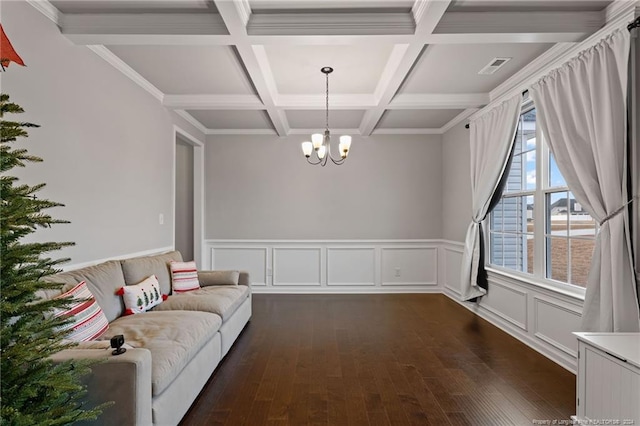 living room featuring ornamental molding, coffered ceiling, dark wood-type flooring, an inviting chandelier, and beamed ceiling