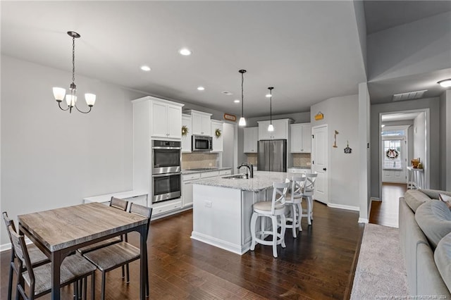 kitchen featuring white cabinetry, sink, stainless steel appliances, and decorative light fixtures