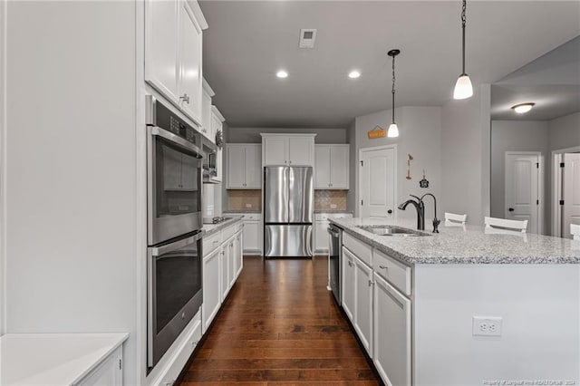 kitchen featuring pendant lighting, sink, dark hardwood / wood-style floors, an island with sink, and stainless steel appliances