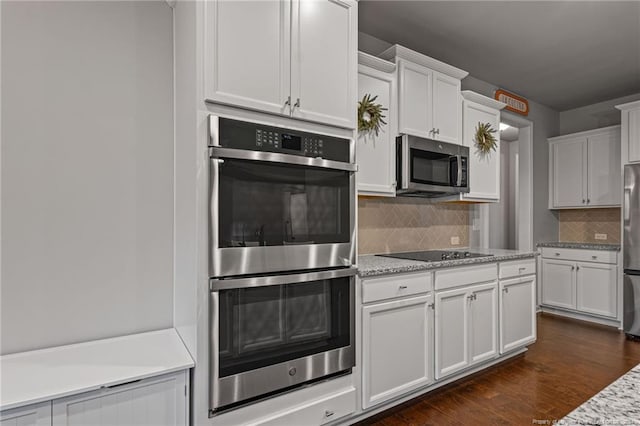 kitchen with backsplash, light stone countertops, dark hardwood / wood-style flooring, white cabinetry, and stainless steel appliances