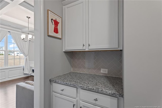 kitchen with white cabinets, light stone counters, tasteful backsplash, a notable chandelier, and dark hardwood / wood-style flooring