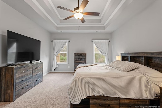 bedroom with a raised ceiling, ceiling fan, and light colored carpet