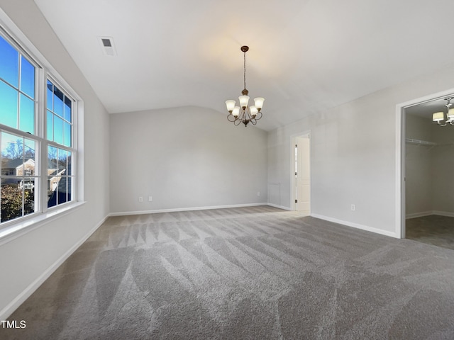 carpeted spare room featuring a notable chandelier and vaulted ceiling