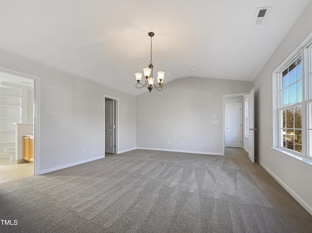 carpeted empty room featuring a chandelier and lofted ceiling