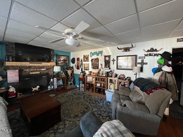 living room with a drop ceiling and ceiling fan