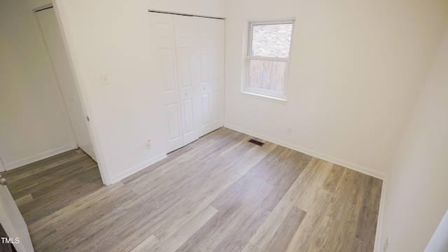 unfurnished bedroom featuring light hardwood / wood-style floors and a closet