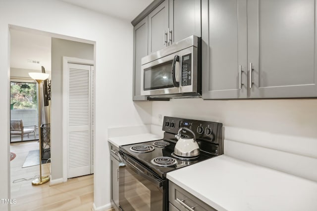 kitchen with light hardwood / wood-style floors, gray cabinets, and black / electric stove