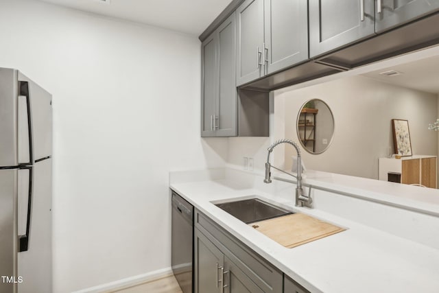 kitchen featuring appliances with stainless steel finishes, gray cabinetry, and sink