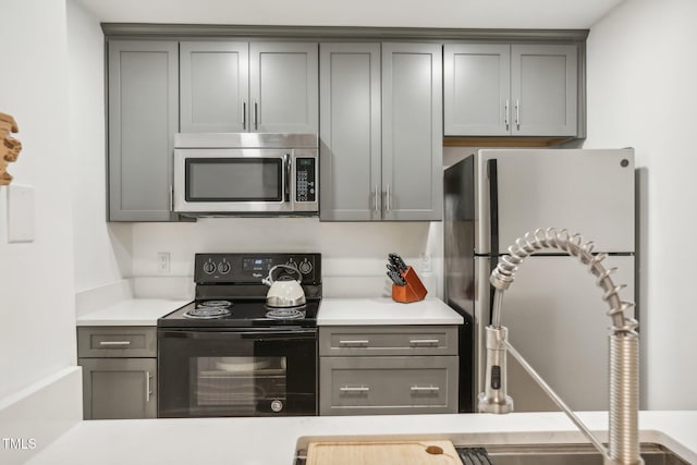 kitchen with gray cabinetry and appliances with stainless steel finishes