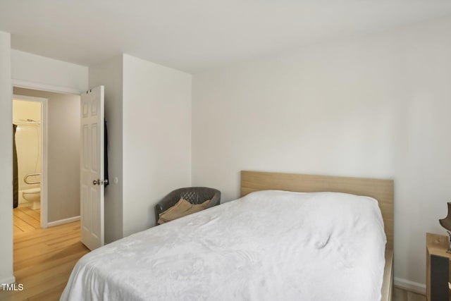 bedroom featuring ensuite bath and hardwood / wood-style floors