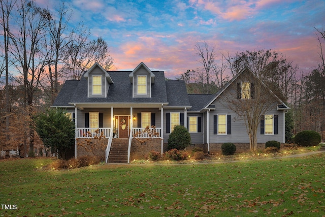 cape cod house featuring a porch and a yard