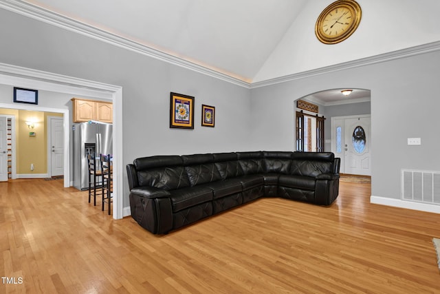 living room with light wood-type flooring, crown molding, and high vaulted ceiling