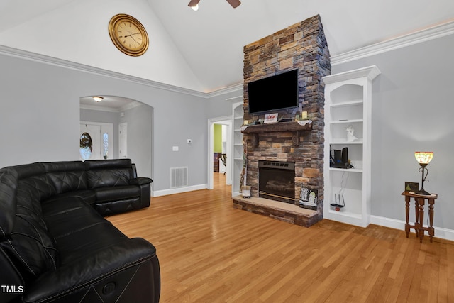 living room featuring ceiling fan, a stone fireplace, high vaulted ceiling, crown molding, and hardwood / wood-style flooring