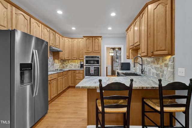 kitchen featuring a kitchen bar, sink, light wood-type flooring, and appliances with stainless steel finishes