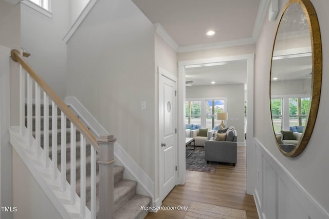 stairs featuring crown molding and hardwood / wood-style flooring