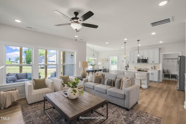 living room with plenty of natural light, ceiling fan, and light hardwood / wood-style flooring