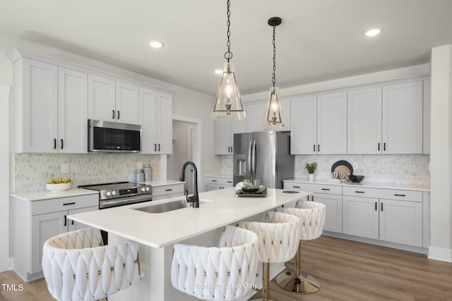 kitchen featuring white cabinetry, sink, stainless steel appliances, light hardwood / wood-style floors, and a kitchen bar