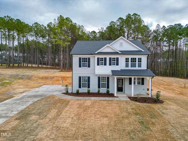 traditional home with a porch, a front lawn, and a shingled roof